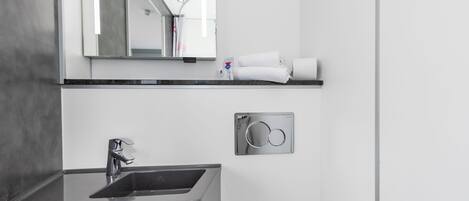 Un baño moderno con lavamanos integrado, espejo y perchero.