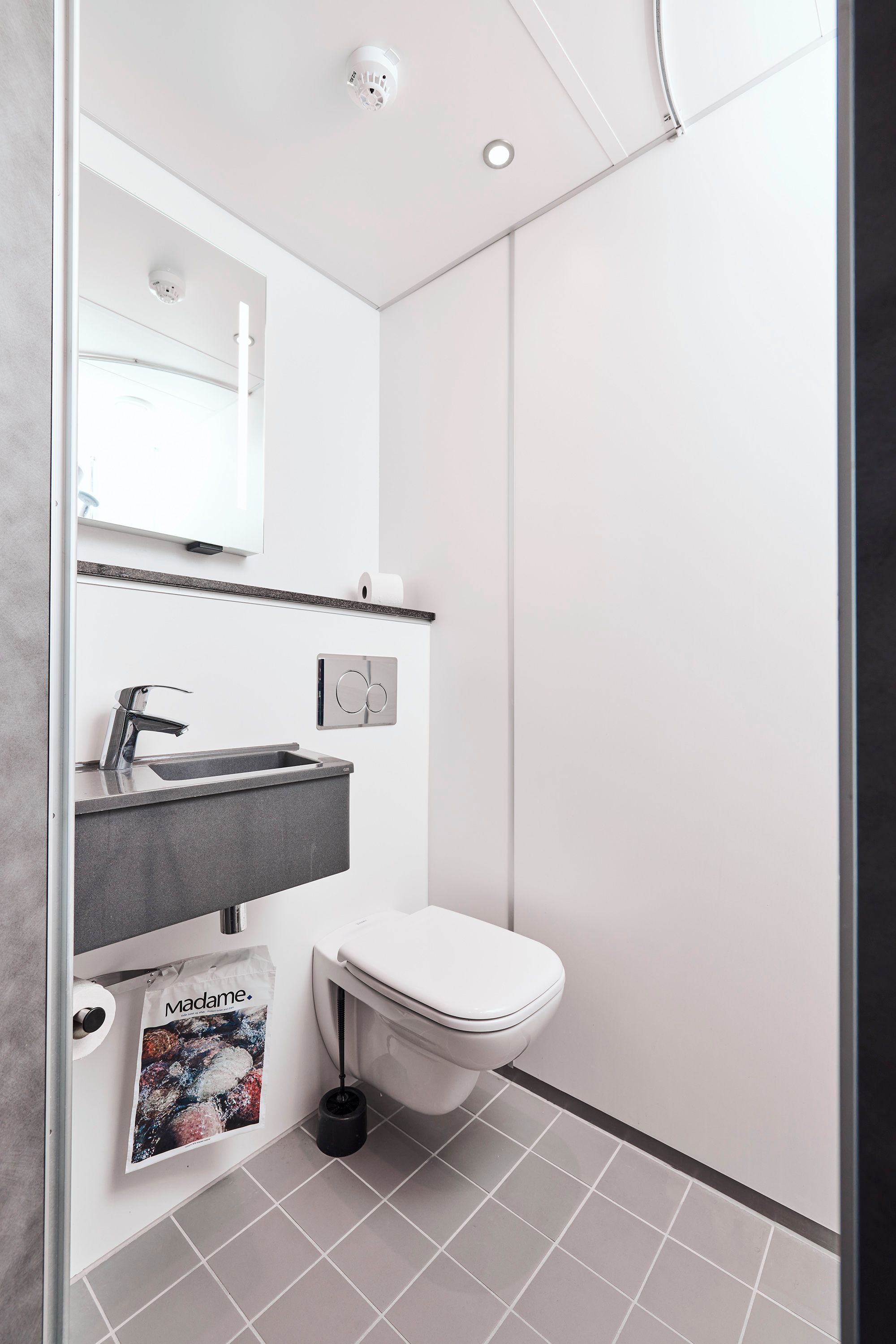 Un baño moderno con inodoro, lavabo y espejo.