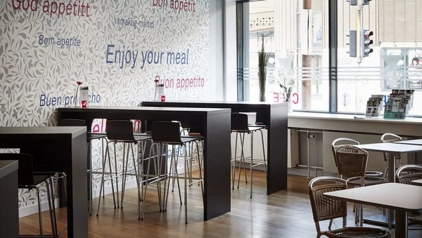 Un intérieur de restaurant moderne avec un mur décoré de motifs, un bar et un espace aménagé pour les clients.