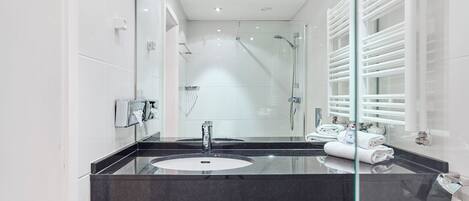 A modern bathroom with a glass-enclosed shower, a black countertop sink, and a large mirror.