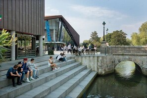 Un edificio moderno con fachada de vidrio y un puente de piedra sobre un canal.