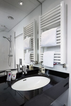 A modern bathroom with a black countertop, white sink, and a glass shower enclosure. - CABINN Vejle Hotel (Vejle)