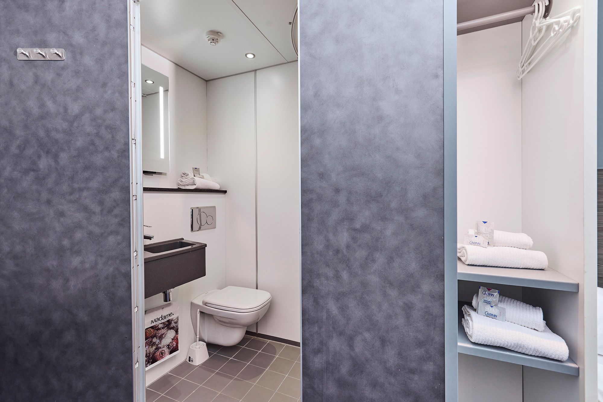 Une salle de bain moderne équipée de toilettes, d’un lavabo et d’un espace pour ranger les serviettes.