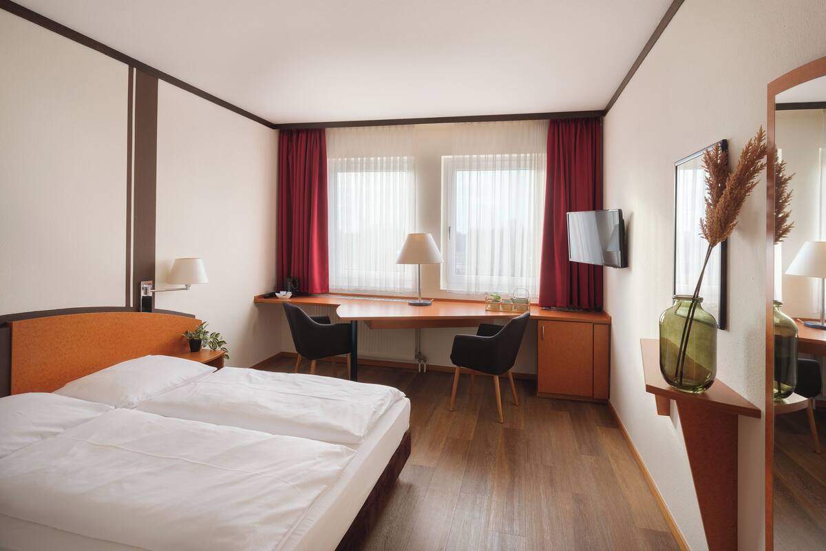 Une chambre d’hôtel équipée d’un lit, d’un bureau, d’une chaise et d’un téléviseur.