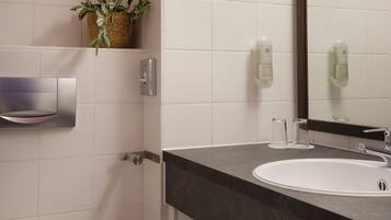Een moderne badkamer met een wit toilet, een wastafel met donker aanrecht, een handdoekhouder en een spiegel.