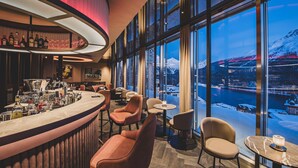 A bar area with a view of a snowy landscape through large windows. - Art Boutique Hotel Monopol (St. Moritz)
