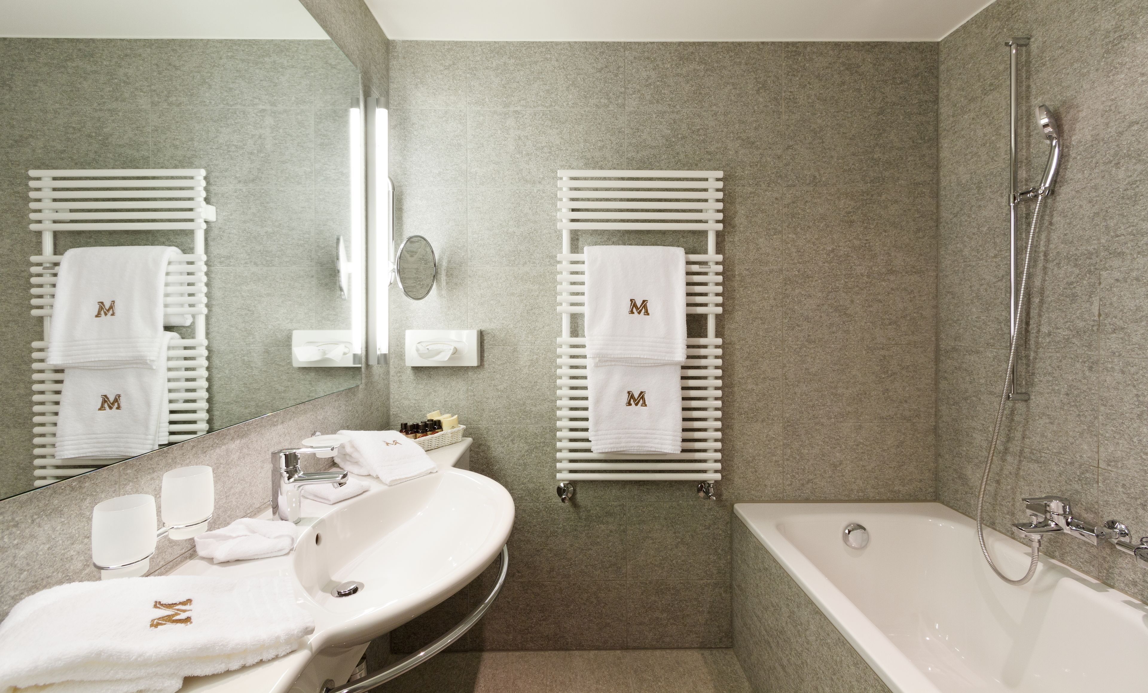 A modern bathroom with a white sink, mirror, and two towel racks with towels.