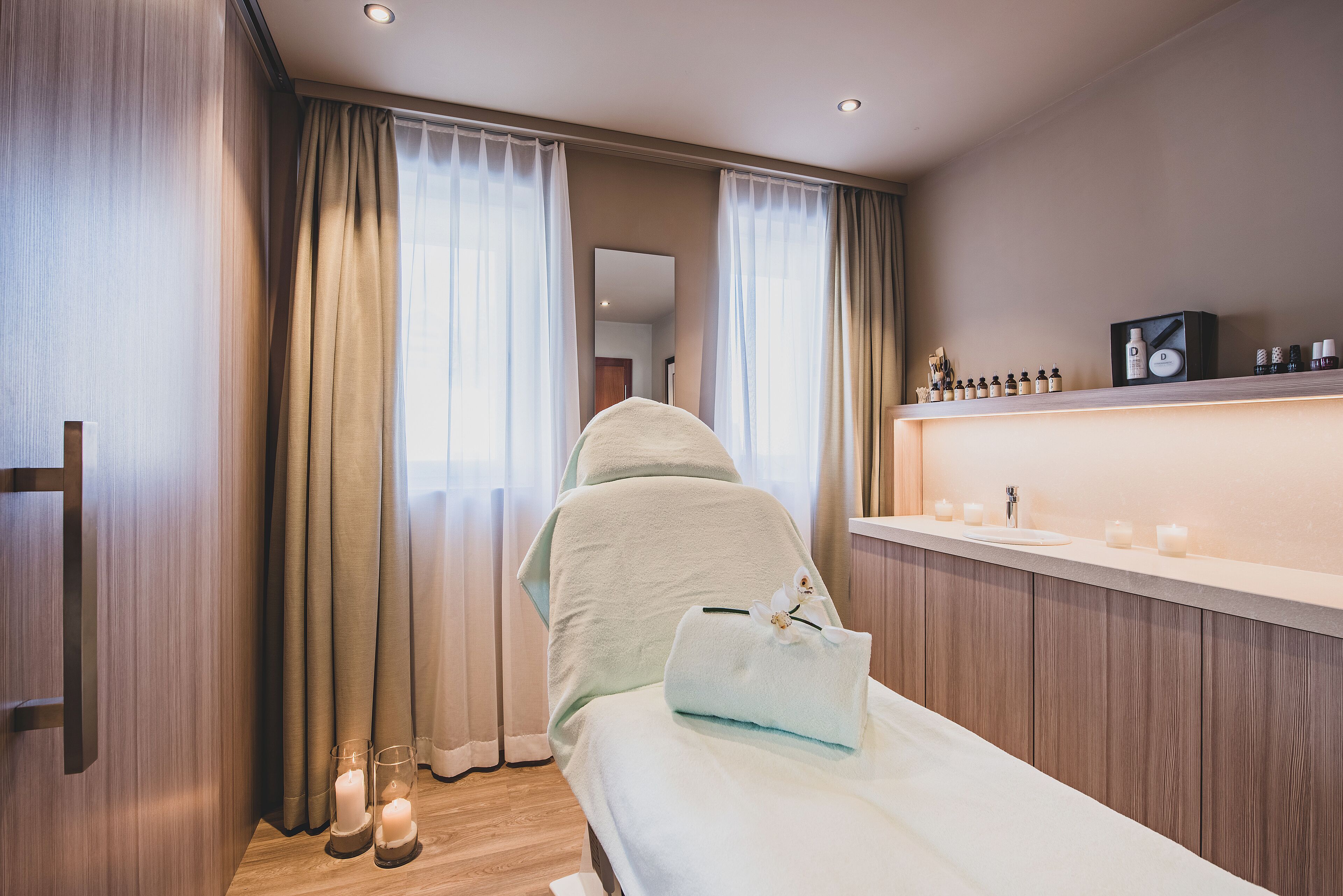 A modern bedroom with a bed, a vanity with toiletries, and a mirror.