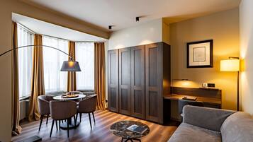 A modern hotel room with a dining area, a sofa, and a desk.