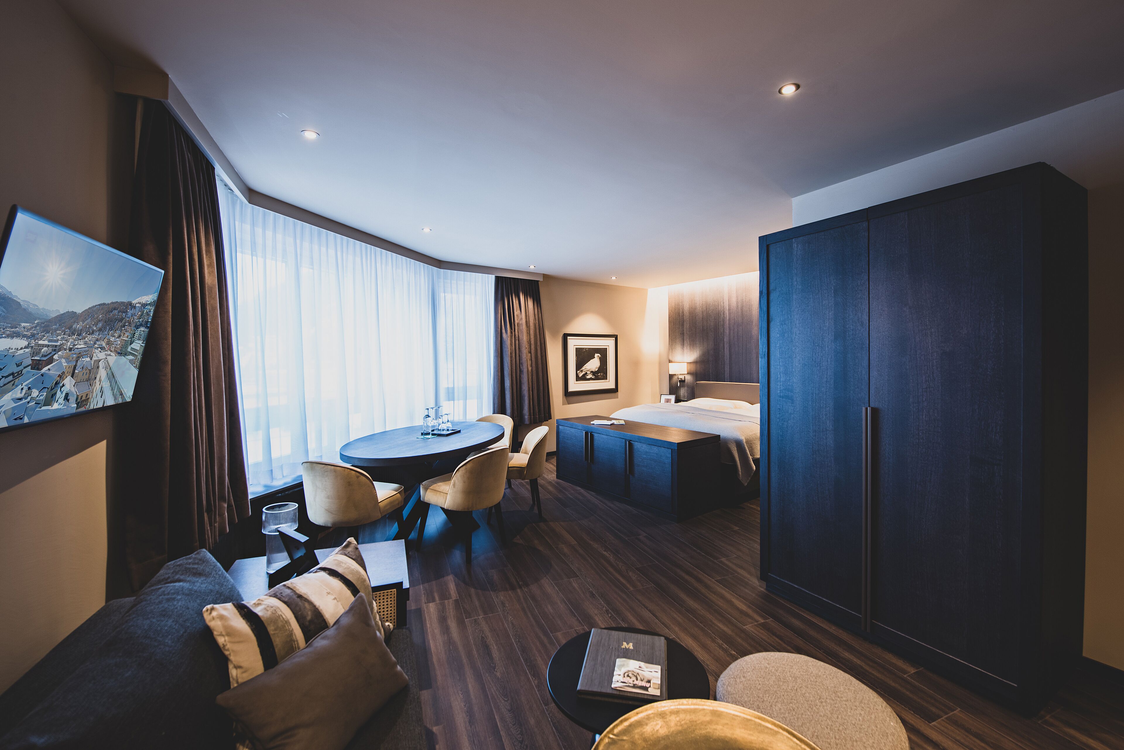 Una habitación de hotel con cama, escritorio, zona de comedor y un armario grande.