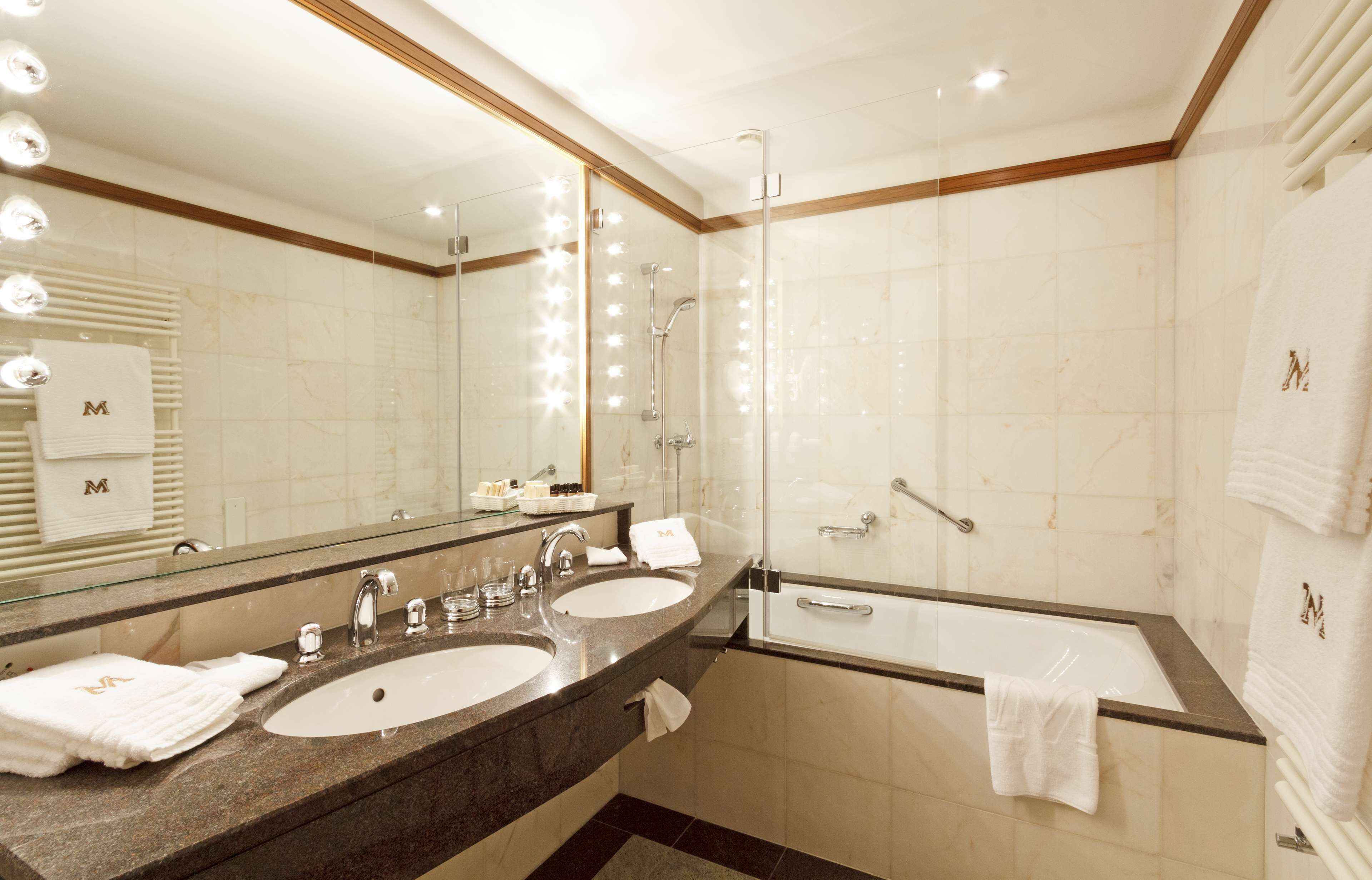 A modern bathroom with two sinks, a large mirror, and a glass-enclosed shower.