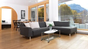 Een moderne woonkamer met een bank, salontafel en een eethoek.