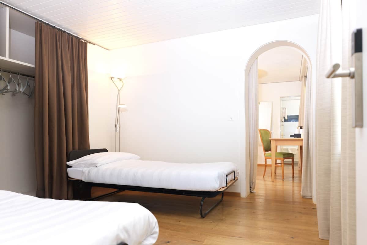 Ein Hotelzimmer mit zwei Einzelbetten, einem Schreibtisch und einem Stuhl.