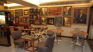 A restaurant with a checkered floor, multiple seating areas, and various framed artworks on the walls. - Hotel Diplomat (New Delhi)
