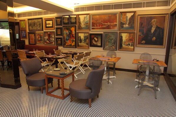 A restaurant with a checkered floor, multiple seating areas, and various framed artworks on the walls.