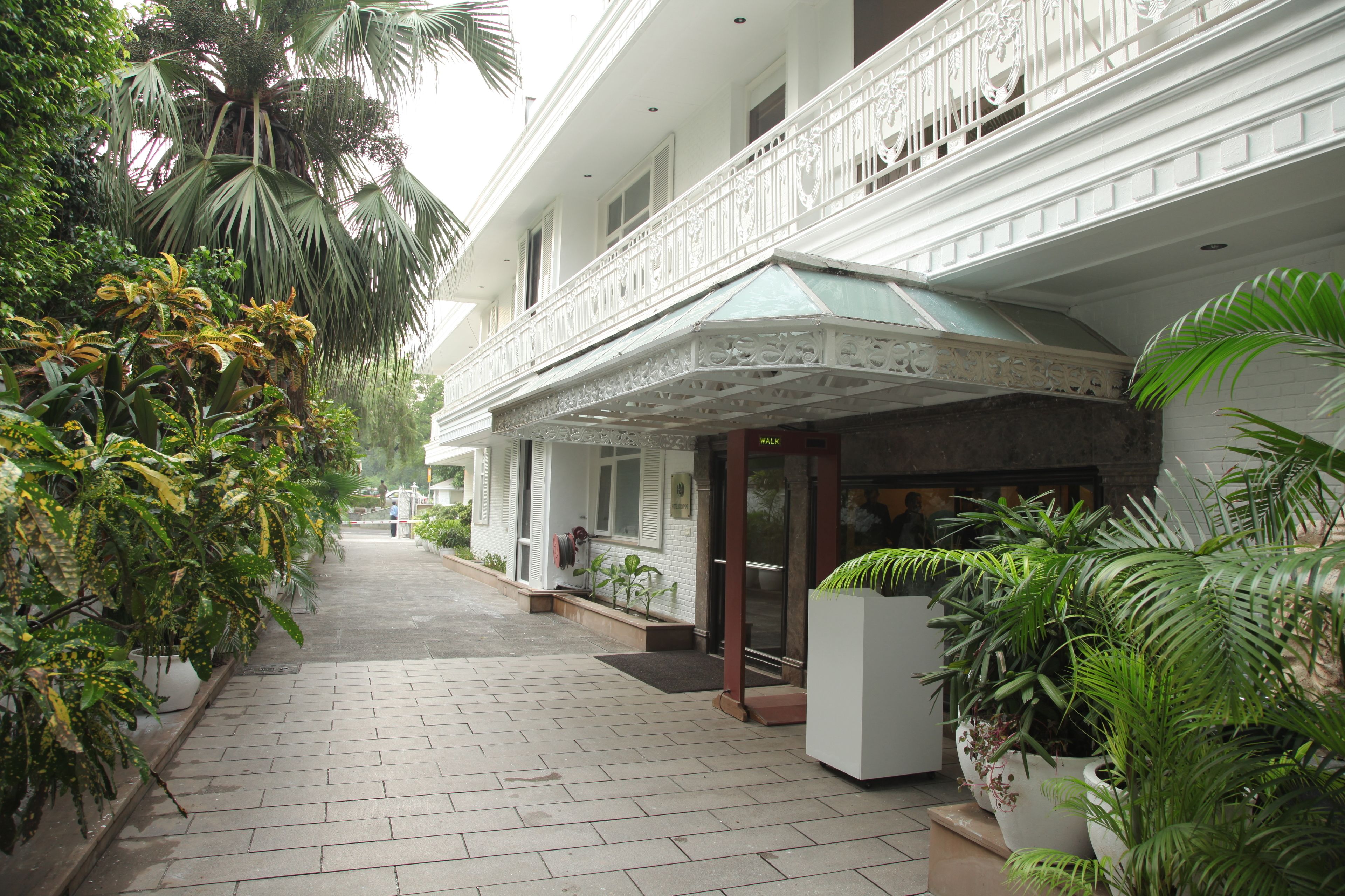 Ein Hotel mit Hauseingang, überdachtem Zugangsbereich, Blumentöpfen und einer weißen Fassade.
