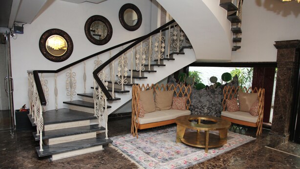A grand staircase with ornate railings, a plush sofa set, and a coffee table in a spacious lobby area. - Hotel Diplomat (New Delhi)