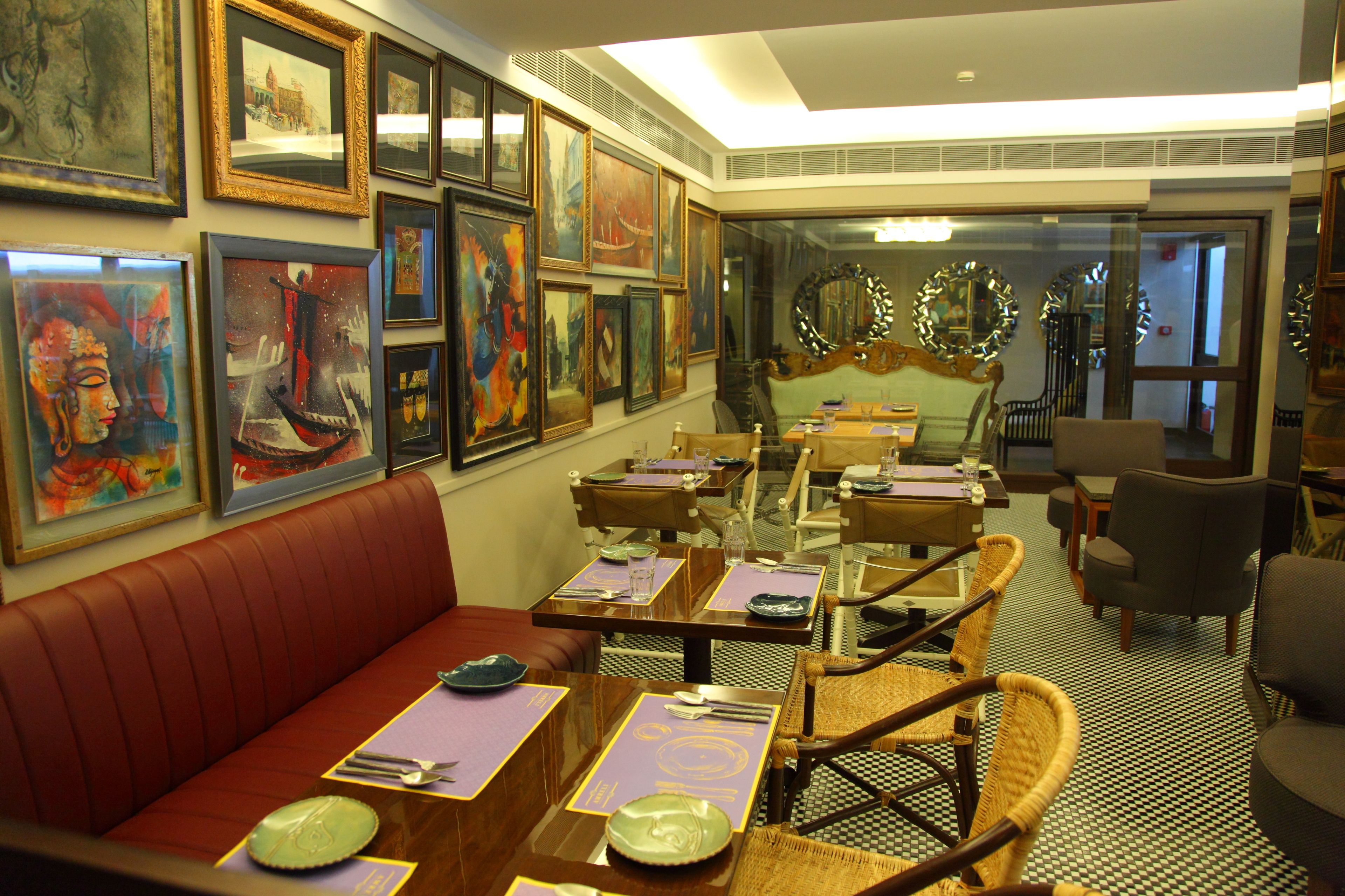 A dining area with red upholstered booths, wooden tables with purple placemats, and framed artwork on the walls.
