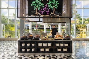 A breakfast buffet setup with various food items and a chef preparing food.
