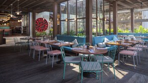 Ein Restaurant mit Außenbereich, Holztischen und Stühlen aus Metall.