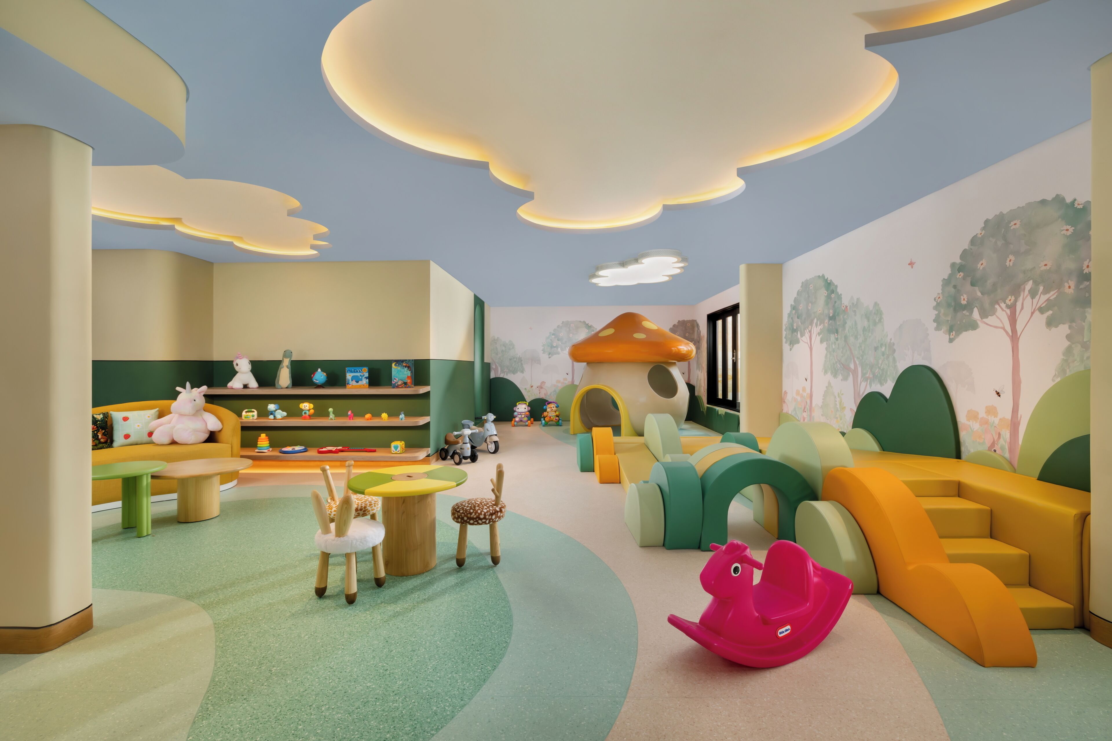 A children's playroom with a soft play area, a seating area with a table, and a bookshelf.