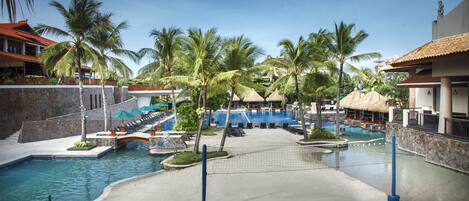 A resort pool area with multiple pools, palm trees, and lounge chairs.