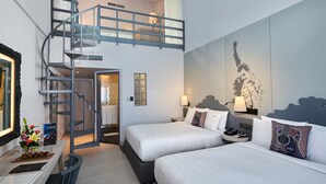 Ein Hotelzimmer mit Doppelbett, Schreibtisch mit Stuhl, einem kleinen Tisch mit Blumenvase, einer Treppe und einem Wandbild.
