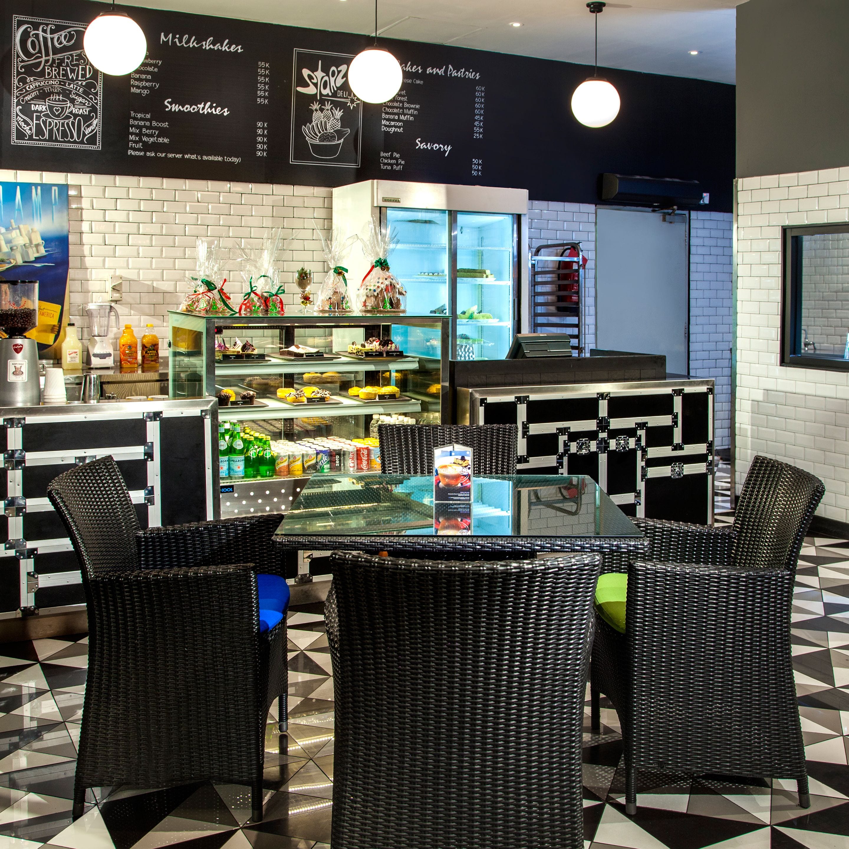 Un café avec un comptoir en verre, des chaises en osier et un menu affiché au mur.