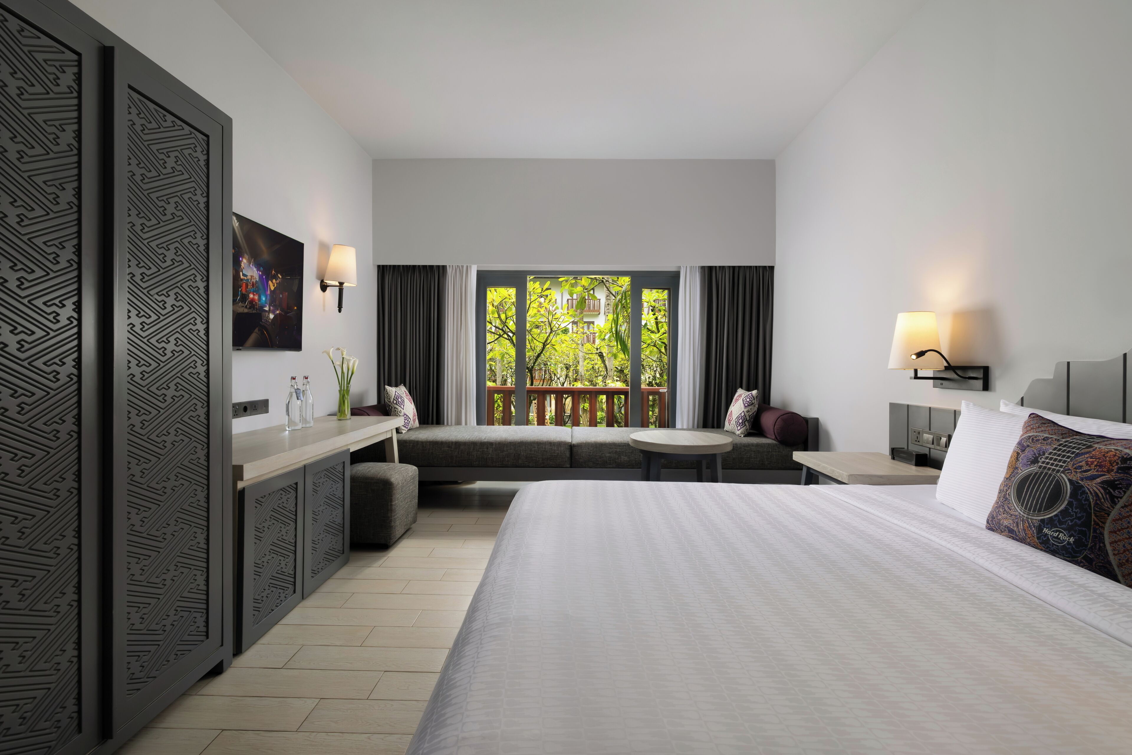 Habitación de hotel con cama, zona de estar, escritorio y vistas a zonas verdes.