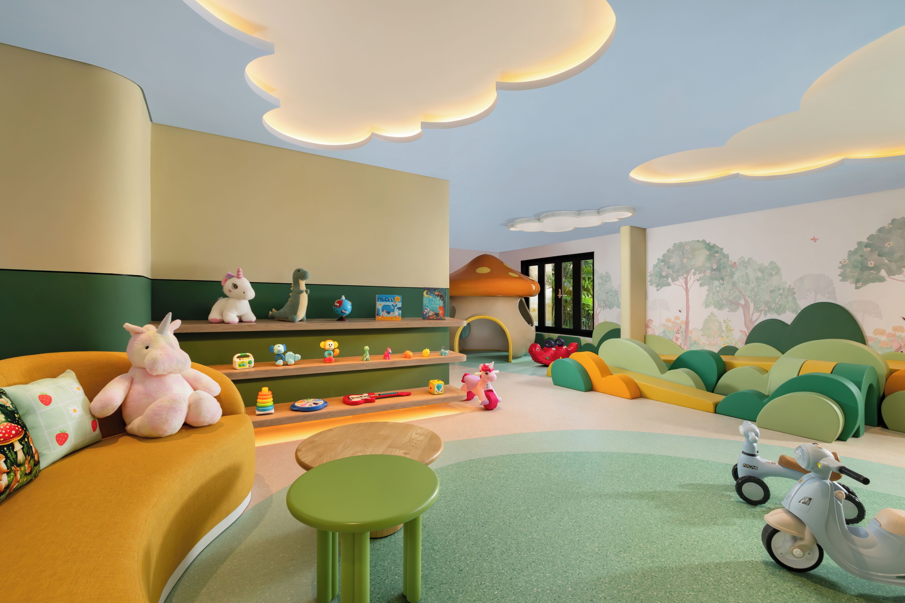 A children's play area with a sofa, a green stool, a toy scooter, and a shelf with various toys.