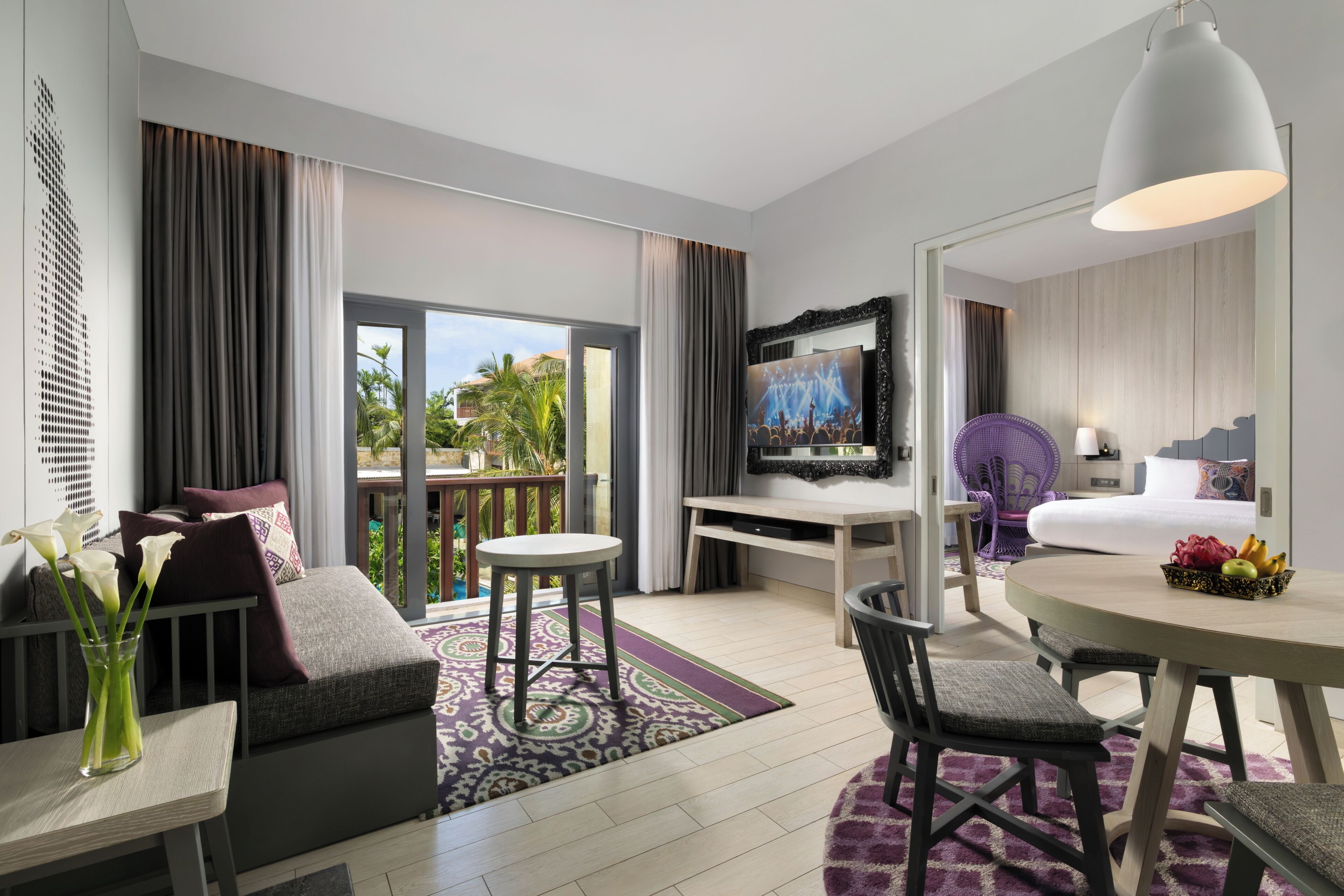 A hotel room with a balcony, a dining area, a bed, and a TV.
