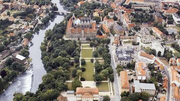 Vista aérea de un pueblo histórico con un río, edificios y una imponente construcción similar a un castillo.