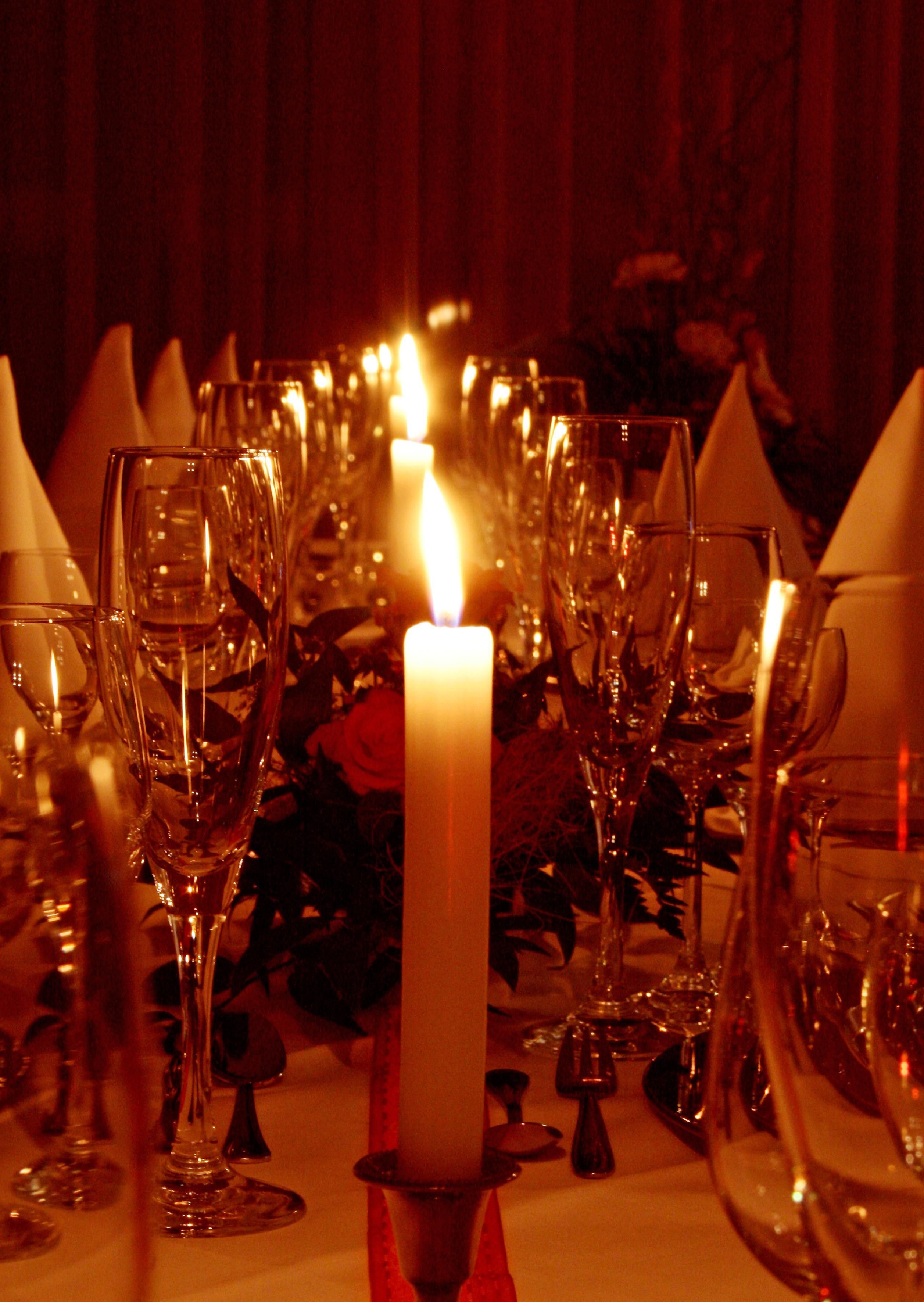 Mesa dispuesta para cenar con varias copas de vino y un candelabro encendido en el centro.