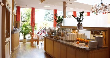 Una barra de desayuno con diversos alimentos y una zona de estar con una silla.