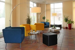 Un área de descanso moderna con asientos, una mesita de centro y plantas en macetas.