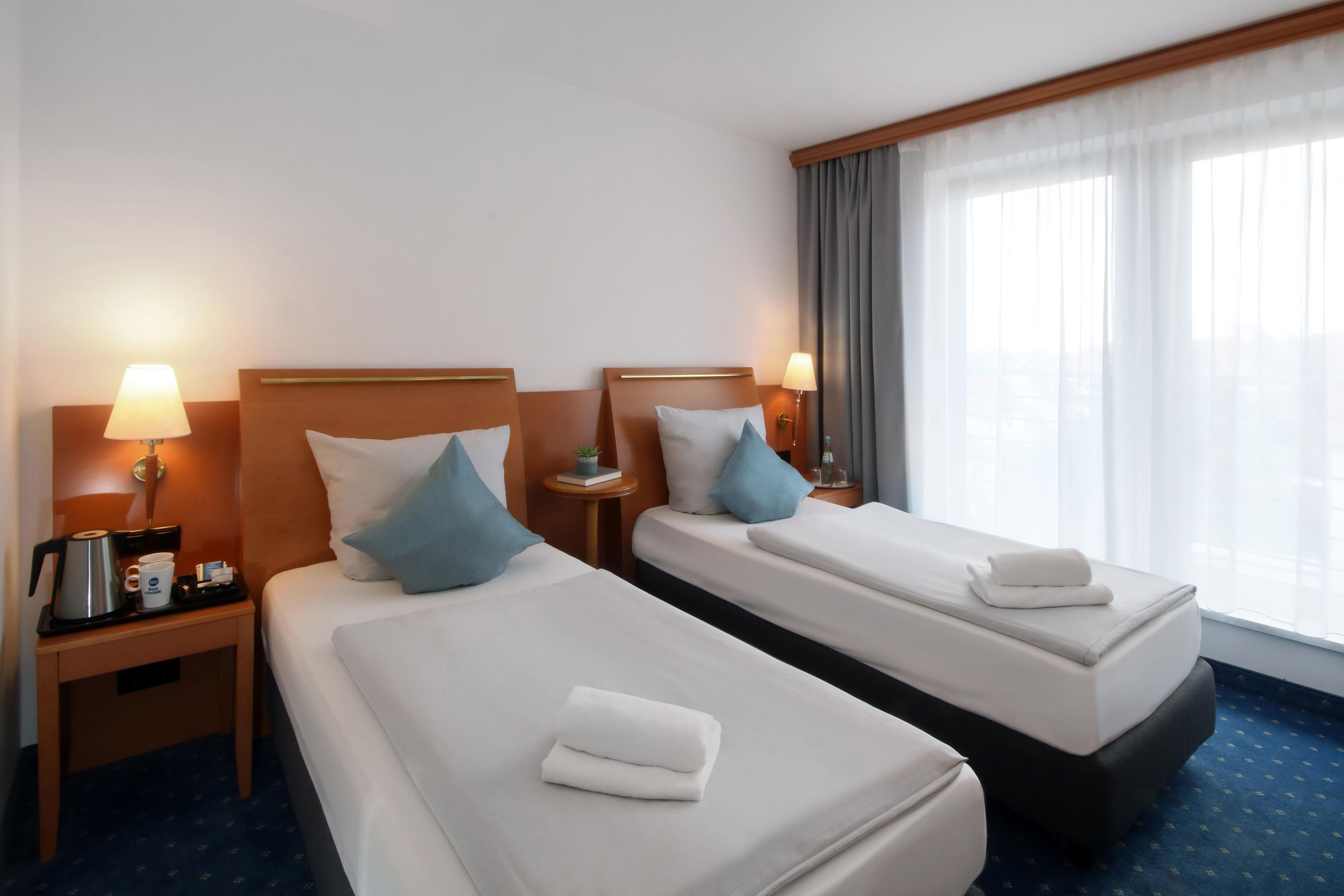 Une chambre d’hôtel avec deux lits, chacun équipé d’un oreiller, d’une table de chevet avec une lampe et d’une machine à café.