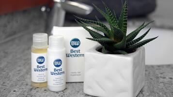A bathroom counter with a potted aloe vera plant, three bottles of Best Western bath and body products, and a Best Western branded box.