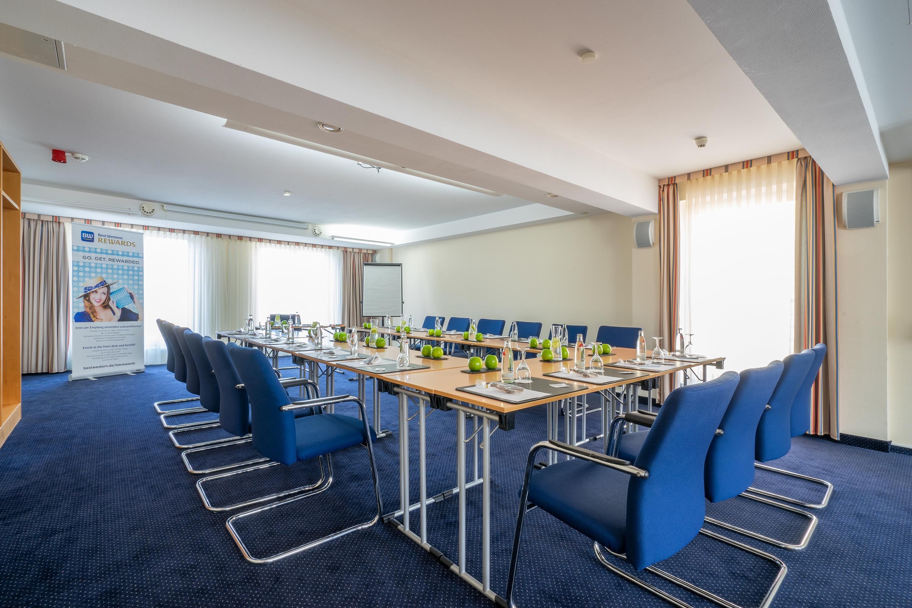 Een vergaderruimte met een lange tafel, blauwe stoelen en een spandoek waarop loyaliteitsprogramma's worden aangeboden.