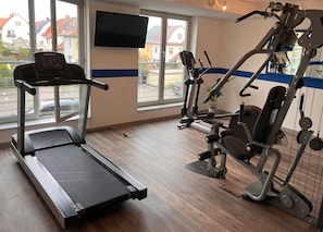 A gym with a treadmill, elliptical, and weight machines.