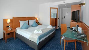 Une chambre d’hôtel comprenant un lit, des tables de chevet, un bureau avec un téléphone et un miroir.