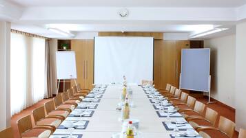 Een vergaderzaal met een lange tafel, klaar voor een vergadering, voorzien van stoelen, een whiteboard en een projectiescherm.