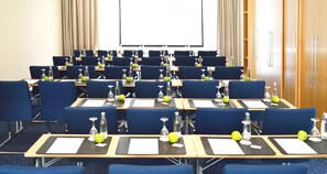 A conference room with rows of tables, chairs, and a projector screen. - Best Western Hotel Halle-Merseburg (Merseburg)