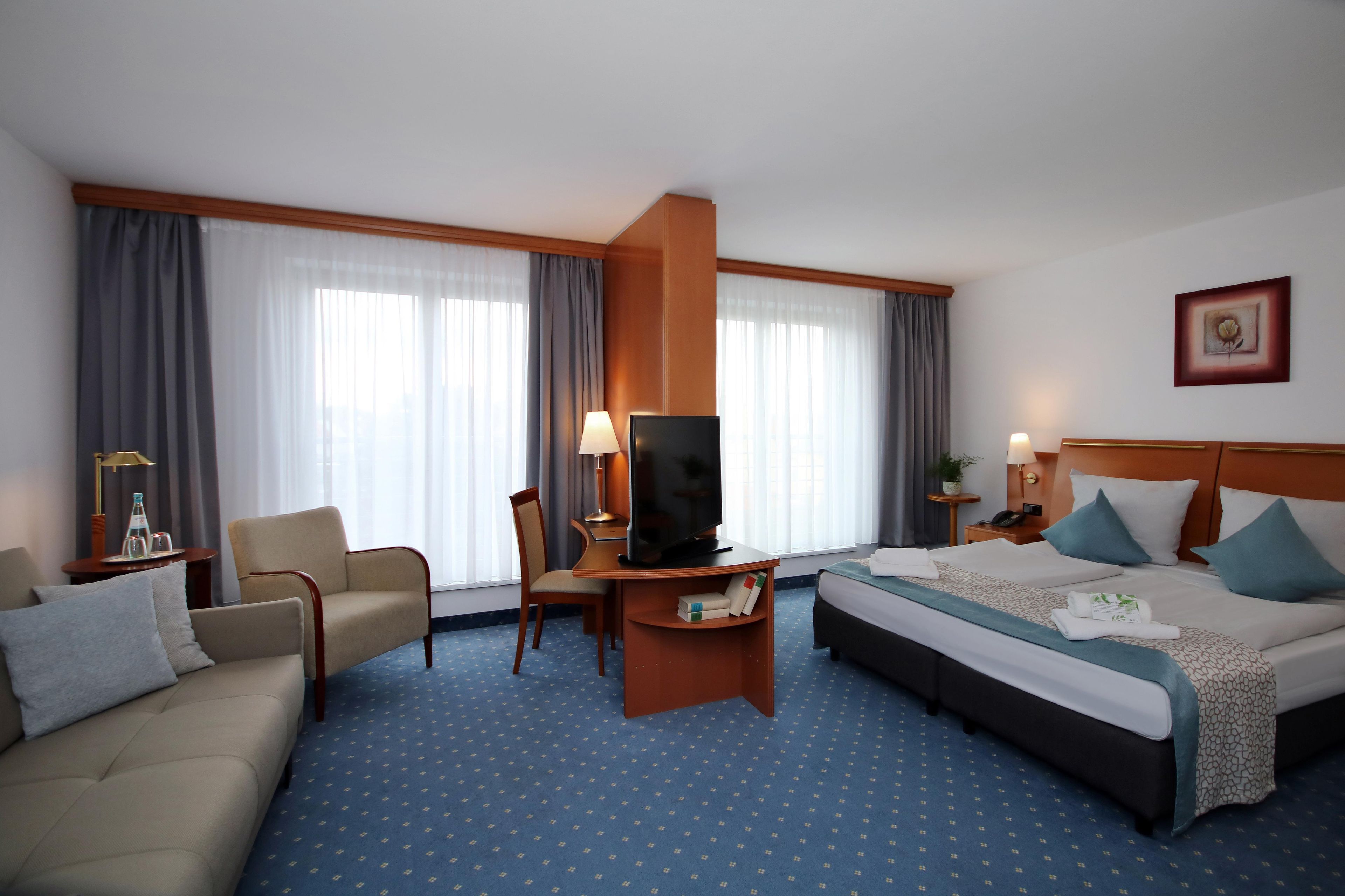 Une chambre d’hôtel avec un lit, un canapé, une télévision, un bureau et une lampe.