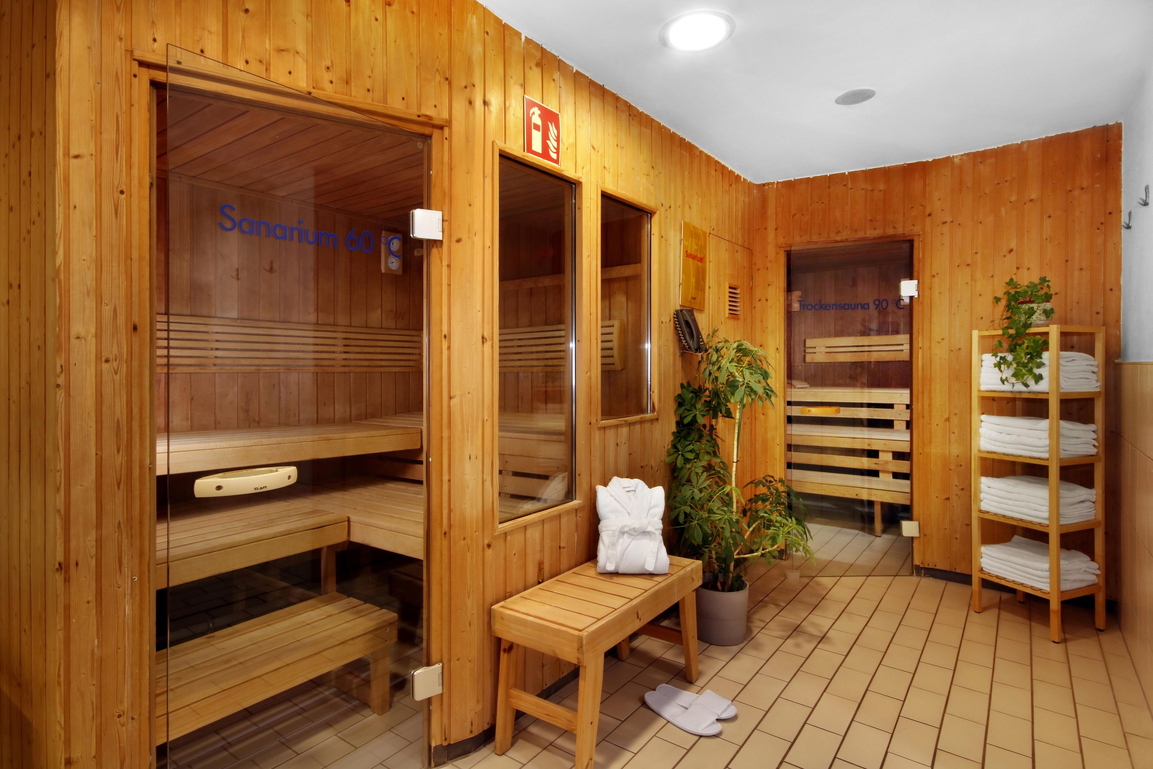 Un sauna con paredes de madera, bancos y un banco con toalla y pantuflas.
