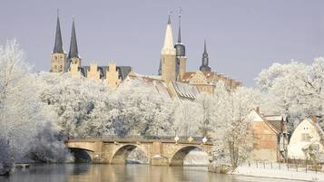 A historic building with multiple spires, a bridge, and frost-covered trees.