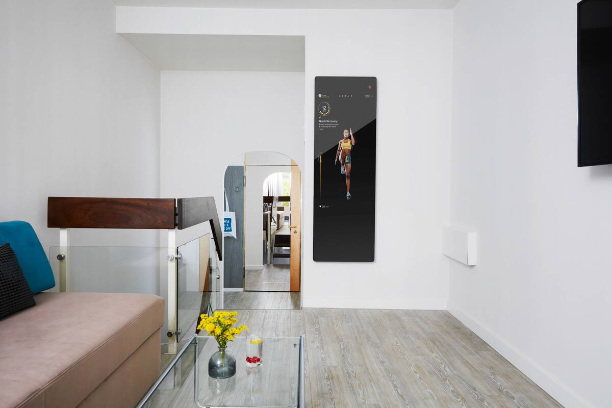 A modern living room with a glass coffee table, a sofa, and a TV mounted on the wall.