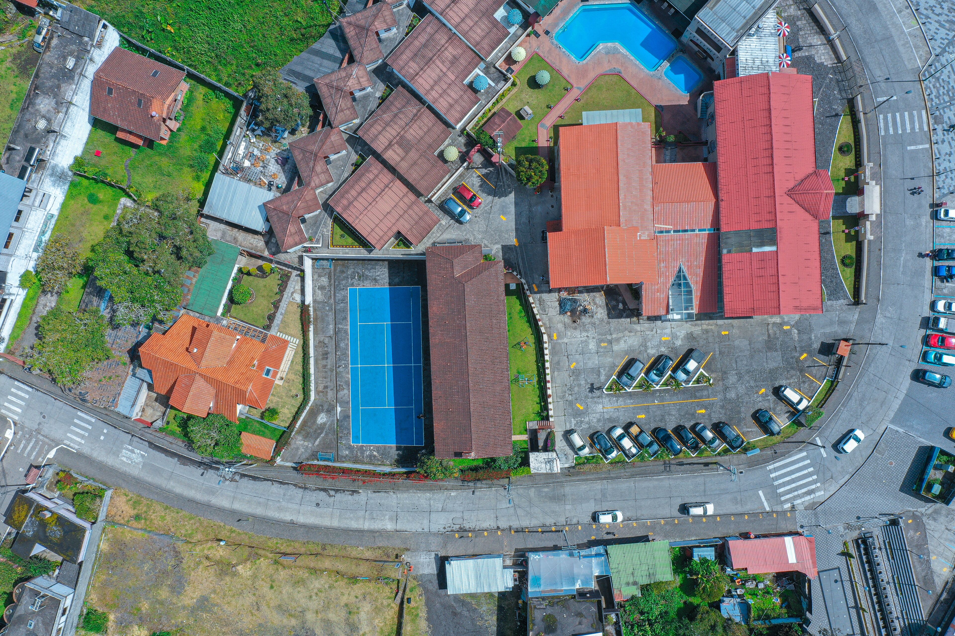 Vista aérea de una zona residencial con varias casas, una piscina y un estacionamiento.