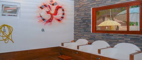 Una habitación con pared de piedra, un ventanal grande e iluminación empotrada en el techo.