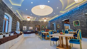 Un restaurante con paredes de piedra, sillas azules y una araña.