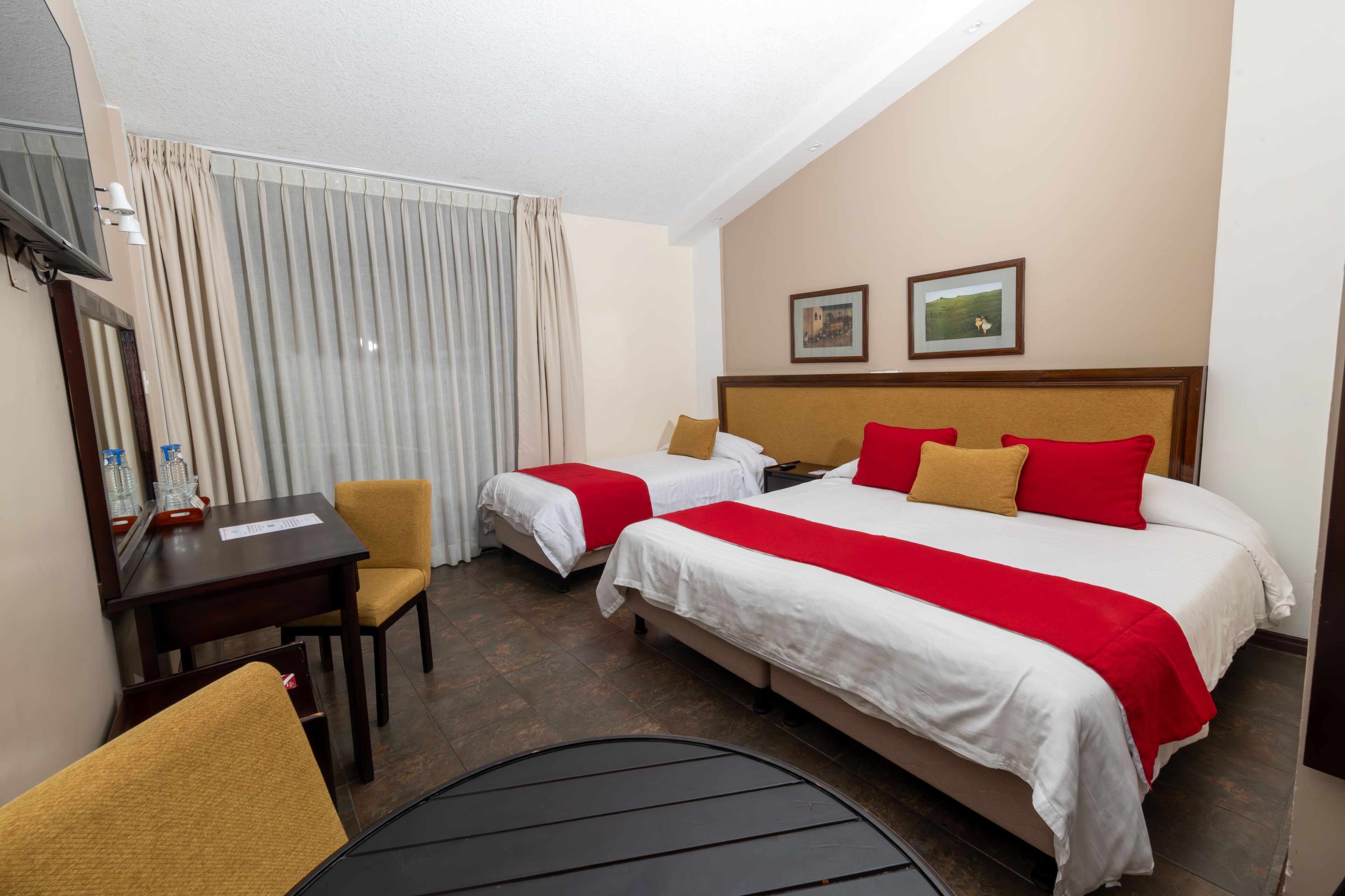 Ein Hotelzimmer mit zwei Betten, einem Schreibtisch, einem Stuhl und einem kleinen Tisch.